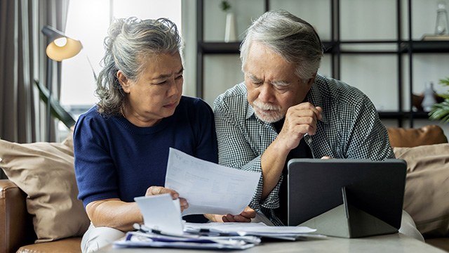 Retired Asian couple looking at bills